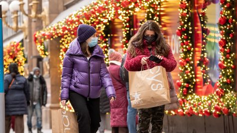 NEW YORK, NEW YORK - DECEMBER 02: People carry shopping bags by holiday decorations outside of Macys in Herald Square on December 02, 2020 in New York City. Many holiday events have been canceled or adjusted with additional safety measures due to the ongoing coronavirus (COVID-19) pandemic. (Photo by Noam Galai/Getty Images)