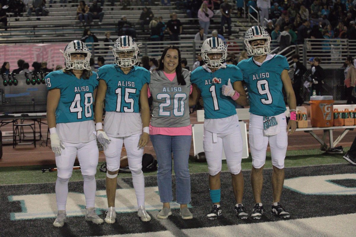 Señora Sepe wears senior player Luke Jones jersey and poses for a photo with football team captains.